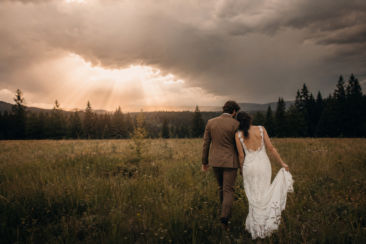 Newlyweds crossing a ranch meadow beneath a dramatic sky